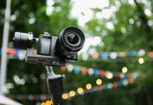 Best Mirrorless Cameras in 2025: Professional Testing & Buying Guide this is an image of A mirrorless camera with a stabilized monopod and remote control. On the background of the fair in the park