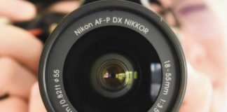 Nikon D5600 Review Closeup picture of the camera lens of the Nikon d5600 dslr, held by a photographer.