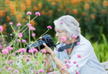 Best Digital Camera Under $400 woman using digital camera in garden, senior woman in her 60s in a garden photographing flowers.