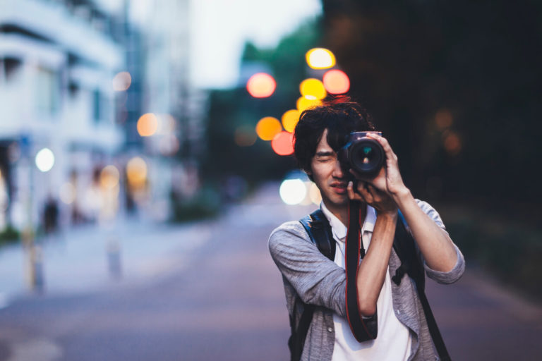 A young Japanese man is taking photos at night in Tokyo