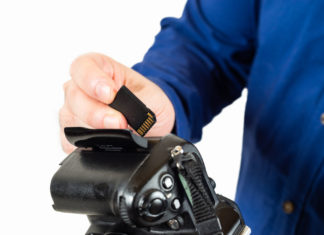 Best Memory Cards for Your Camera Image contains a man inserting a memory card into his camera.